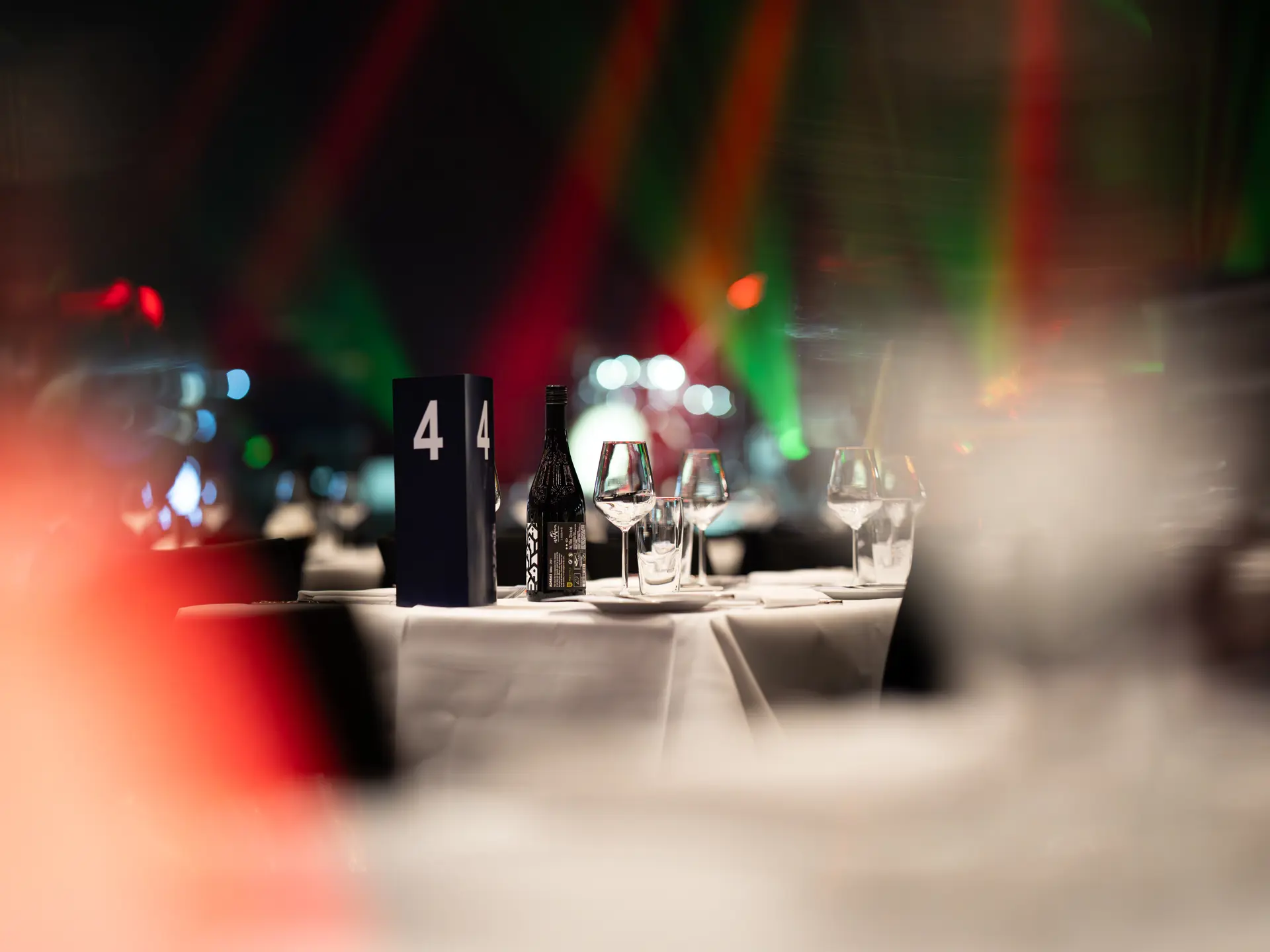 Nærbillede af opdækket bord med vinflaske, glas og nummer til julefrokost i Bella Center.