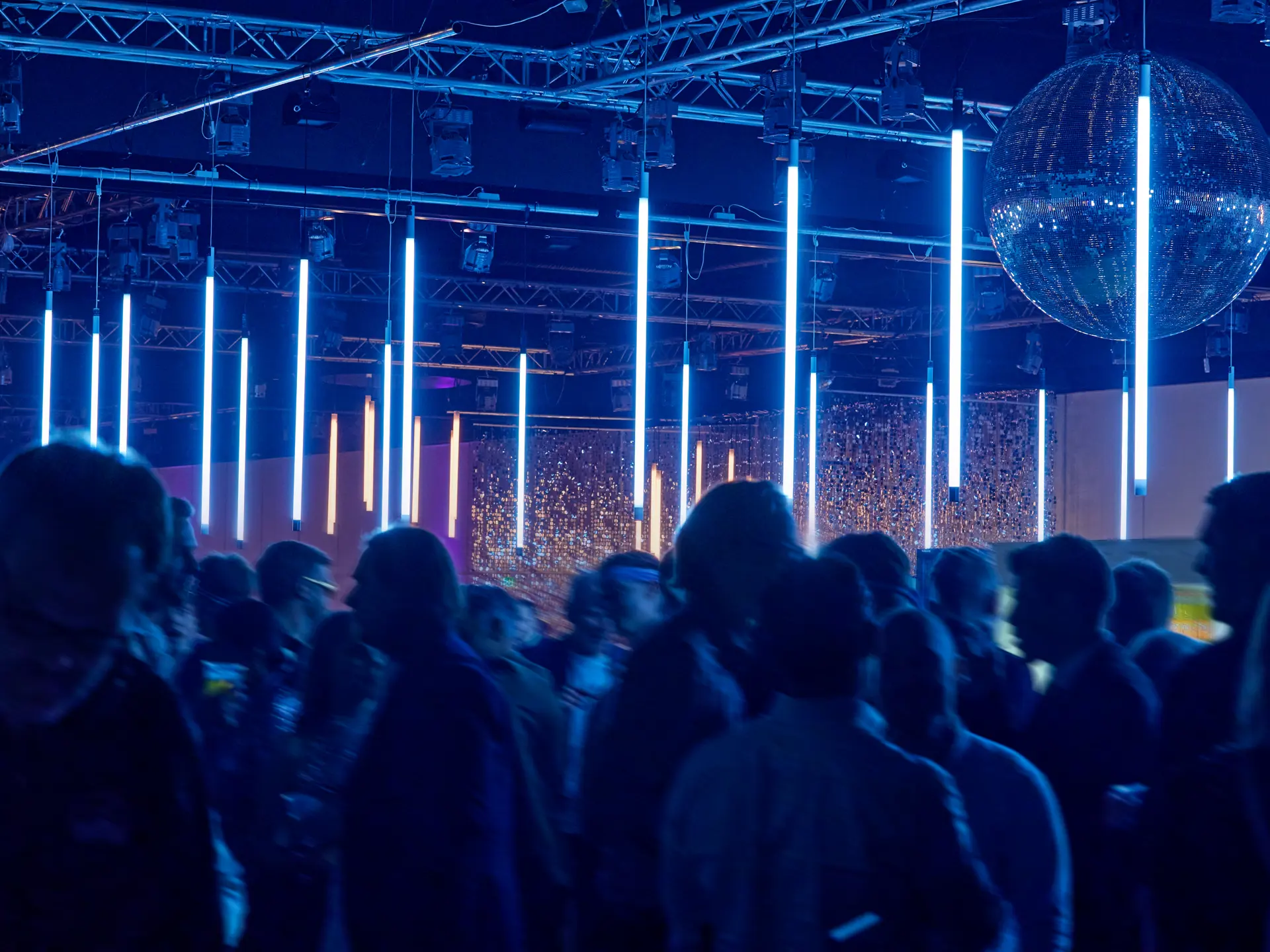 Dansende gæster under blå lysinstallationer og diskokugle til julefrokost i Bella Center.